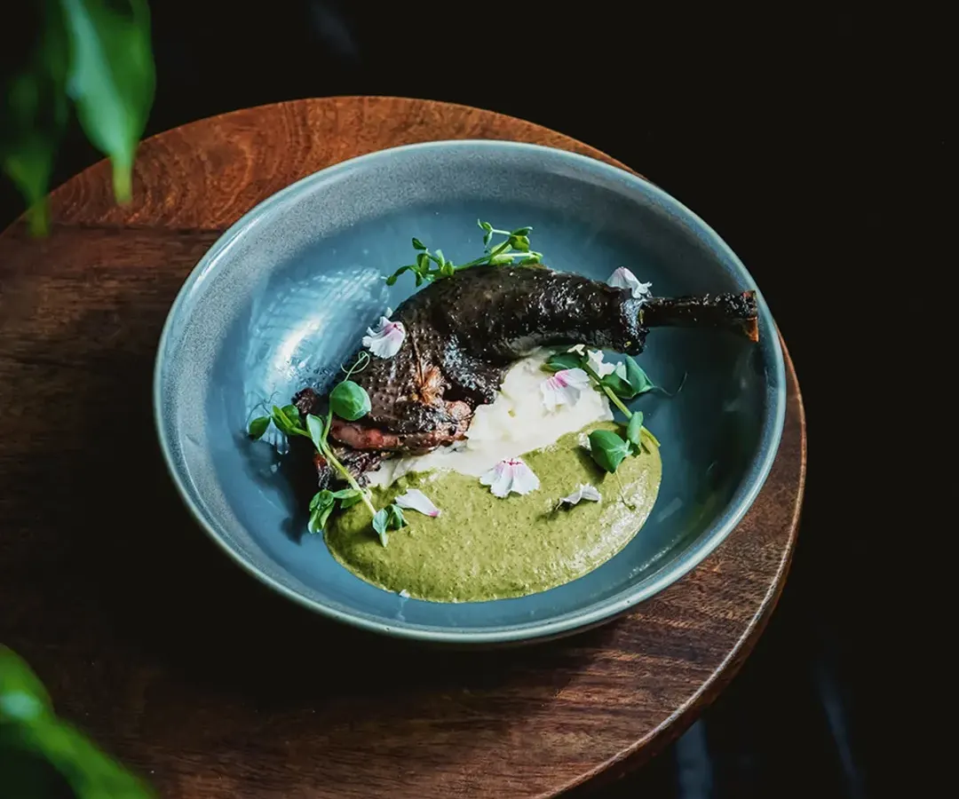 A dish that tells a story of heritage and craft. This is our Kadaknath confit leg, artfully plated with a vibrant green puree and delicate edible flowers. It represents our philosophy of transforming carefully sourced ingredients into culinary art.