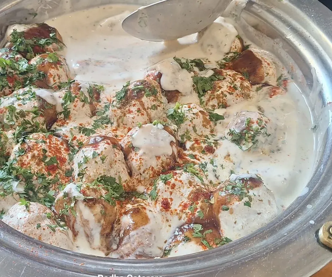 A close-up of our classic Dahi Vada, perfectly soft and soaked in creamy yogurt, garnished with fresh coriander and spices. It's a crowd favorite at every event, from birthday parties to wedding receptions.