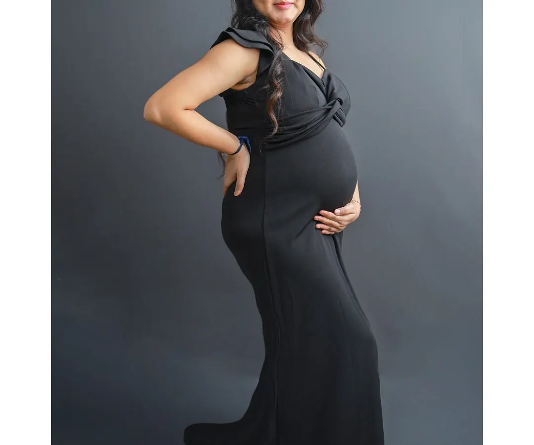 Every mother is a queen, and this portrait is designed to celebrate that. Here, the mom-to-be wears a stunning black maternity gown and a delicate crown, creating a timeless and empowering solo portrait against a classic studio backdrop.