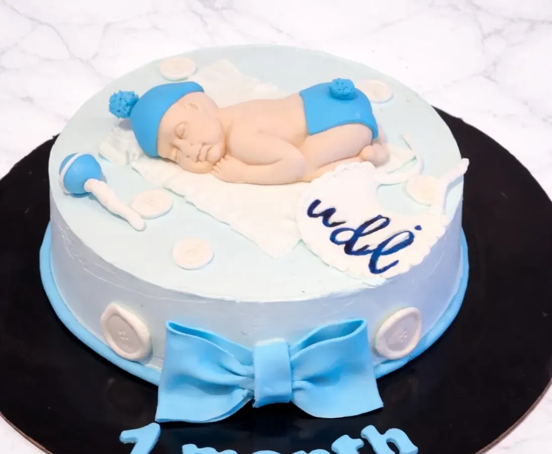 I love marking those precious baby milestones. This 7-month celebration cake features a hand-sculpted sleeping baby made from fondant, complete with a tiny rattle and a personalized name, all on a soft blue buttercream cake.