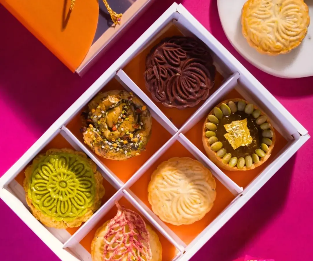 A glimpse inside one of my modern festive gift boxes. Each compartment holds a unique creation, from gold-dusted pumpkin fudge tartlets to intricately molded chocolate biskuts, offering a journey of reinvented Indian flavors.