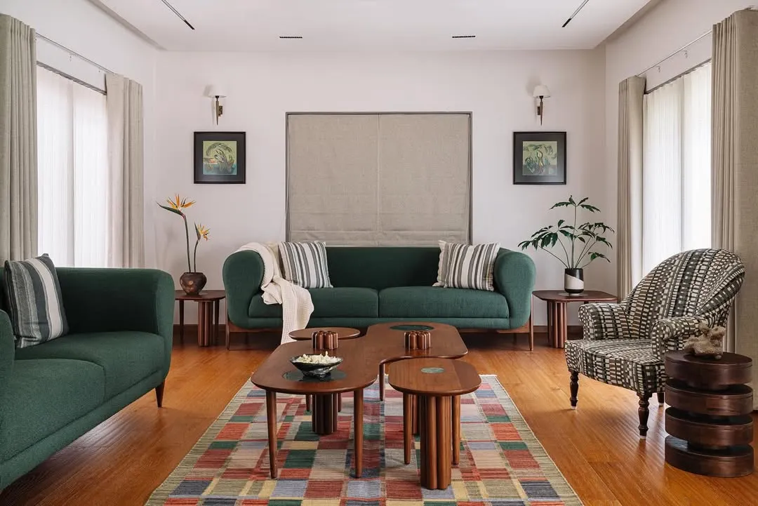 In our Cocoon House project, we curated a living space that feels both sophisticated and deeply personal. The design blends a rich emerald sofa and a patterned armchair with bespoke wooden coffee tables, all grounded by a colorful geometric rug, creating a space that is layered with character and comfort.