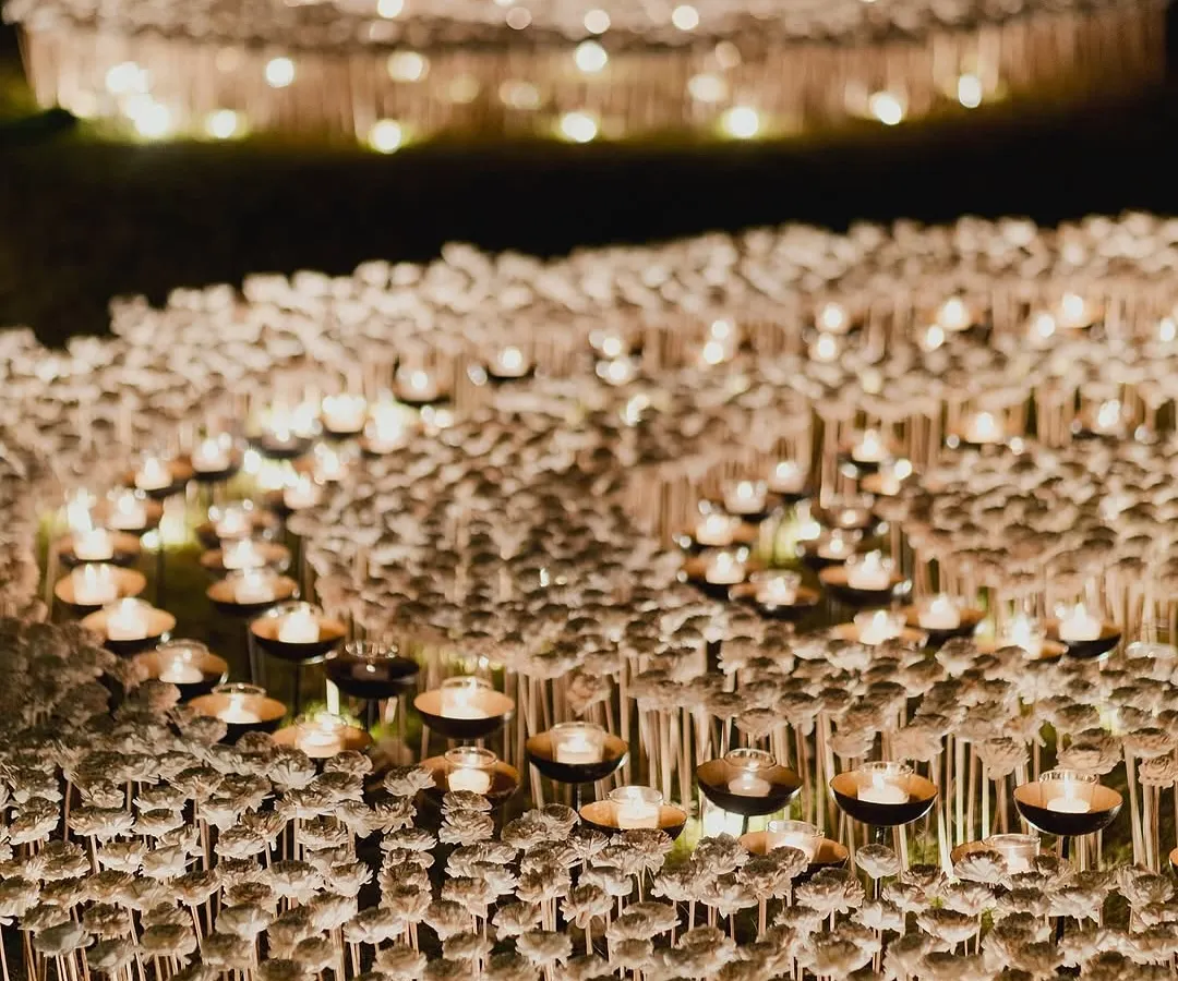 Artistry is at the core of what we do. For this event, we created a breathtaking outdoor installation featuring a field of countless candles and delicate white blooms, designed to evoke a sense of wonder and create an ethereal, glowing landscape under the night sky.