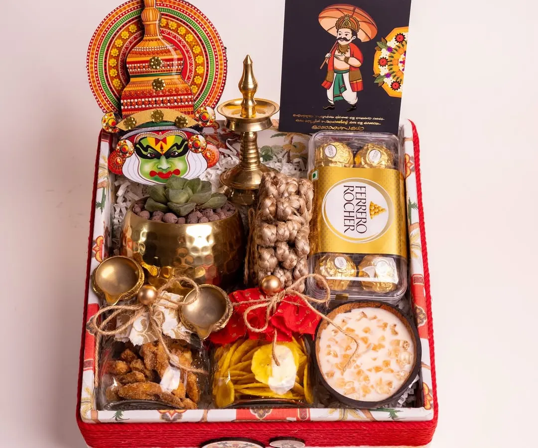 My 'Ponnonam' luxury hamper is a celebration of Onam in a box. It's filled with traditional delights like sharkara varatti and upperi, alongside Ferrero Rocher, a live succulent, and cultural symbols like a Kathakali head and a brass nilavilakku, all presented in a beautifully lined custom box.