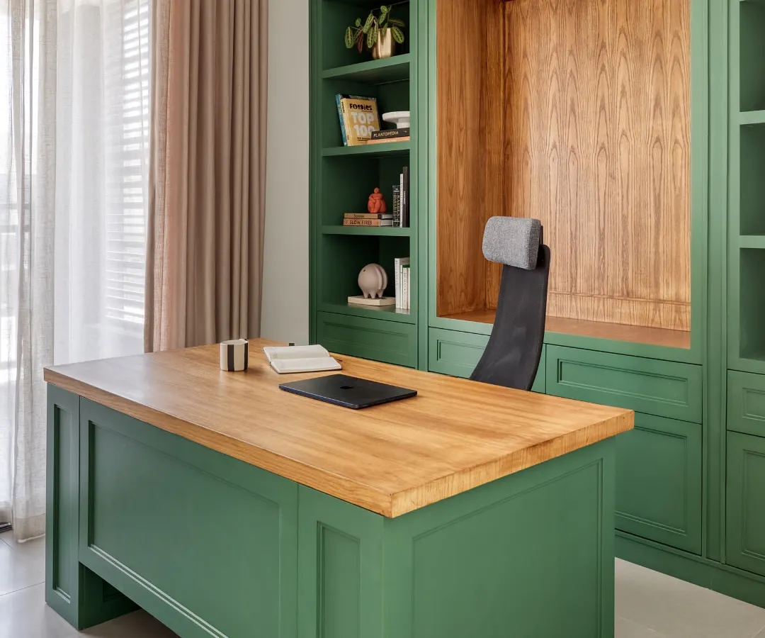 This custom-designed home office in Dubai Hills features a bold bottle green finish paired with a warm oak wood desk and integrated shelving. We designed this space to be a functional and personal sanctuary, balancing rich color with natural light to create a calm, focused environment.