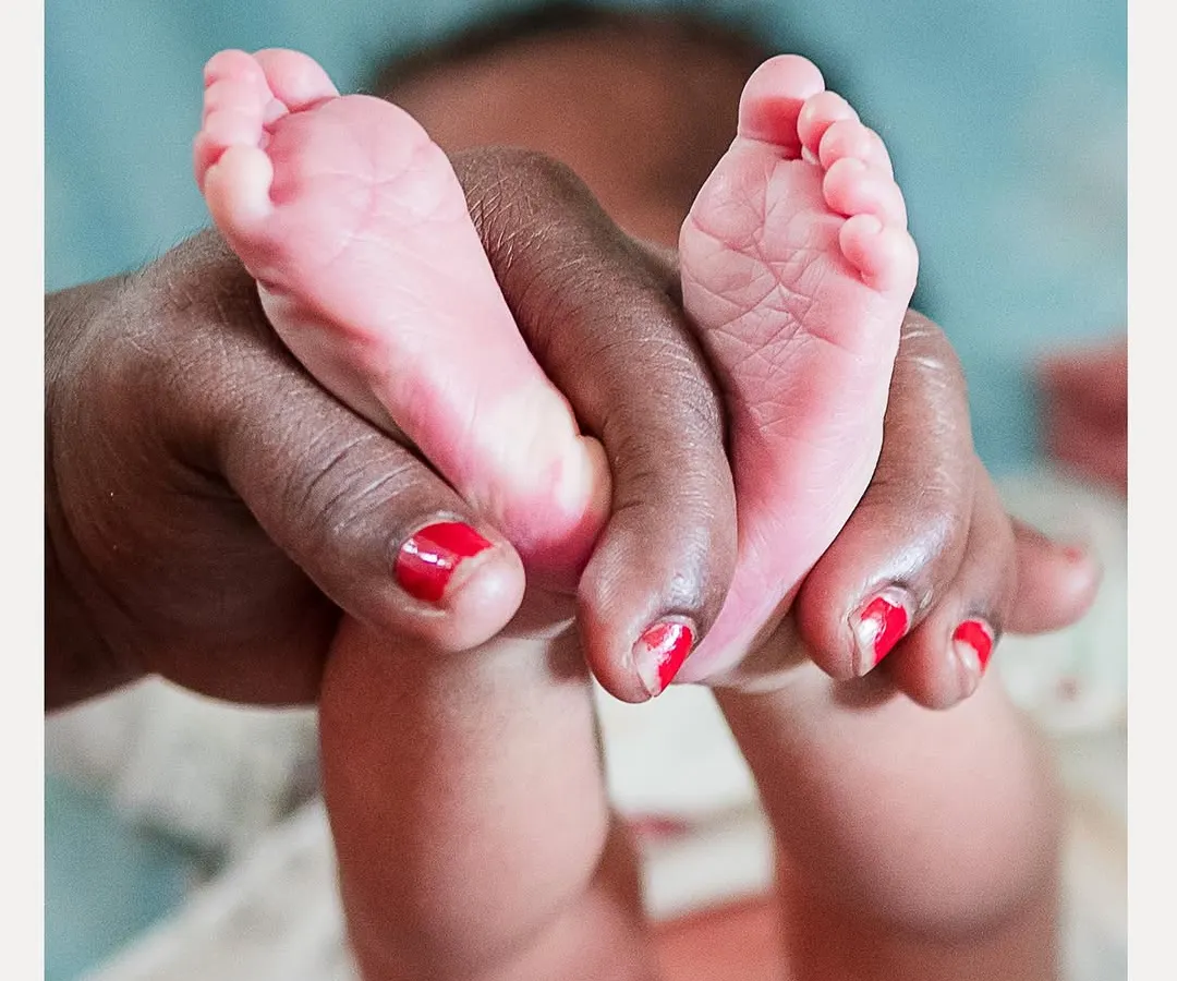 The tiny feet of a newborn, held gently during a naming ceremony. We believe in capturing the delicate details that tell the story of a new beginning.