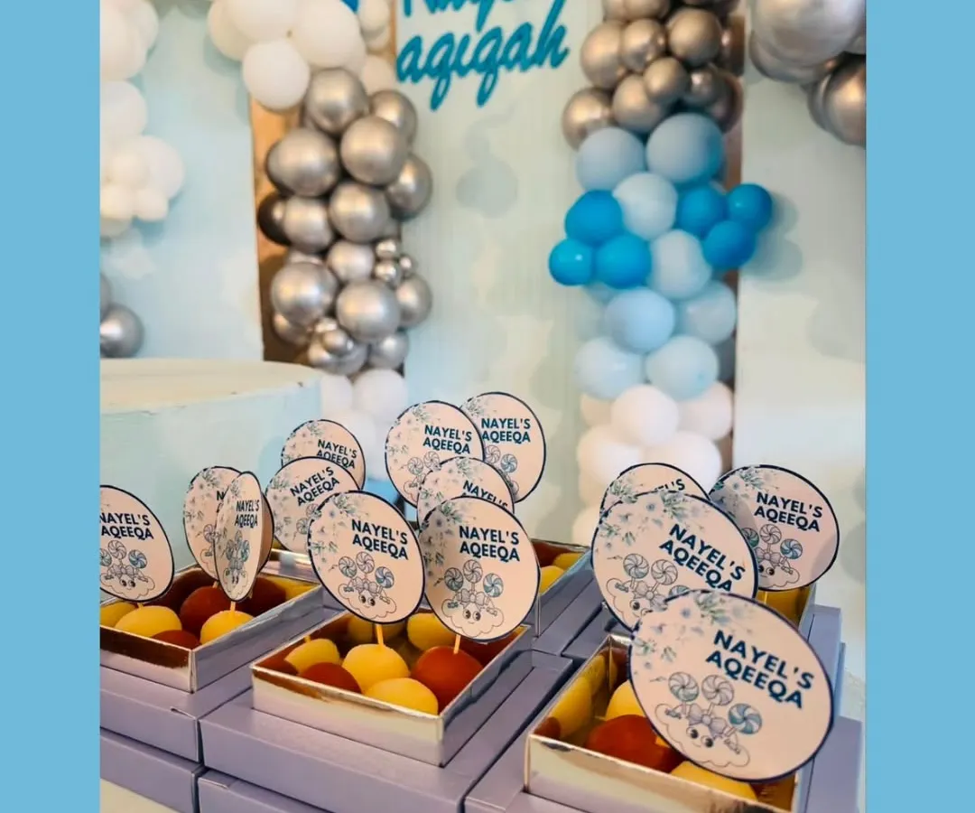 Custom gift boxes we created for an Aqeeqah ceremony. These lavender boxes were filled with sweets and featured personalized toppers with the baby's name, perfectly matching the event's blue and silver decor.