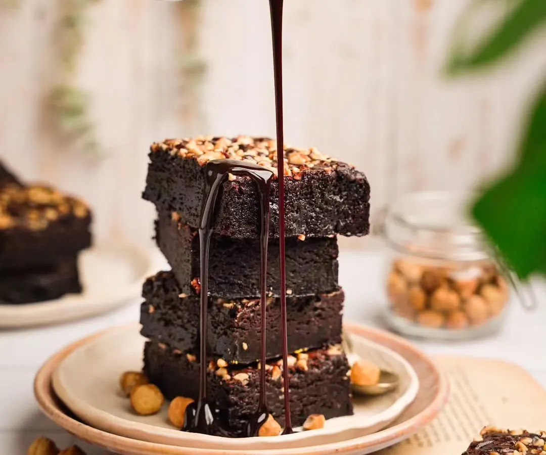 That perfect, luscious pour of chocolate sauce over a stack of hazelnut brownies. For me, action shots like this are crucial. They create a moment of craving and show the decadent, gooey texture that makes a dessert truly unforgettable.