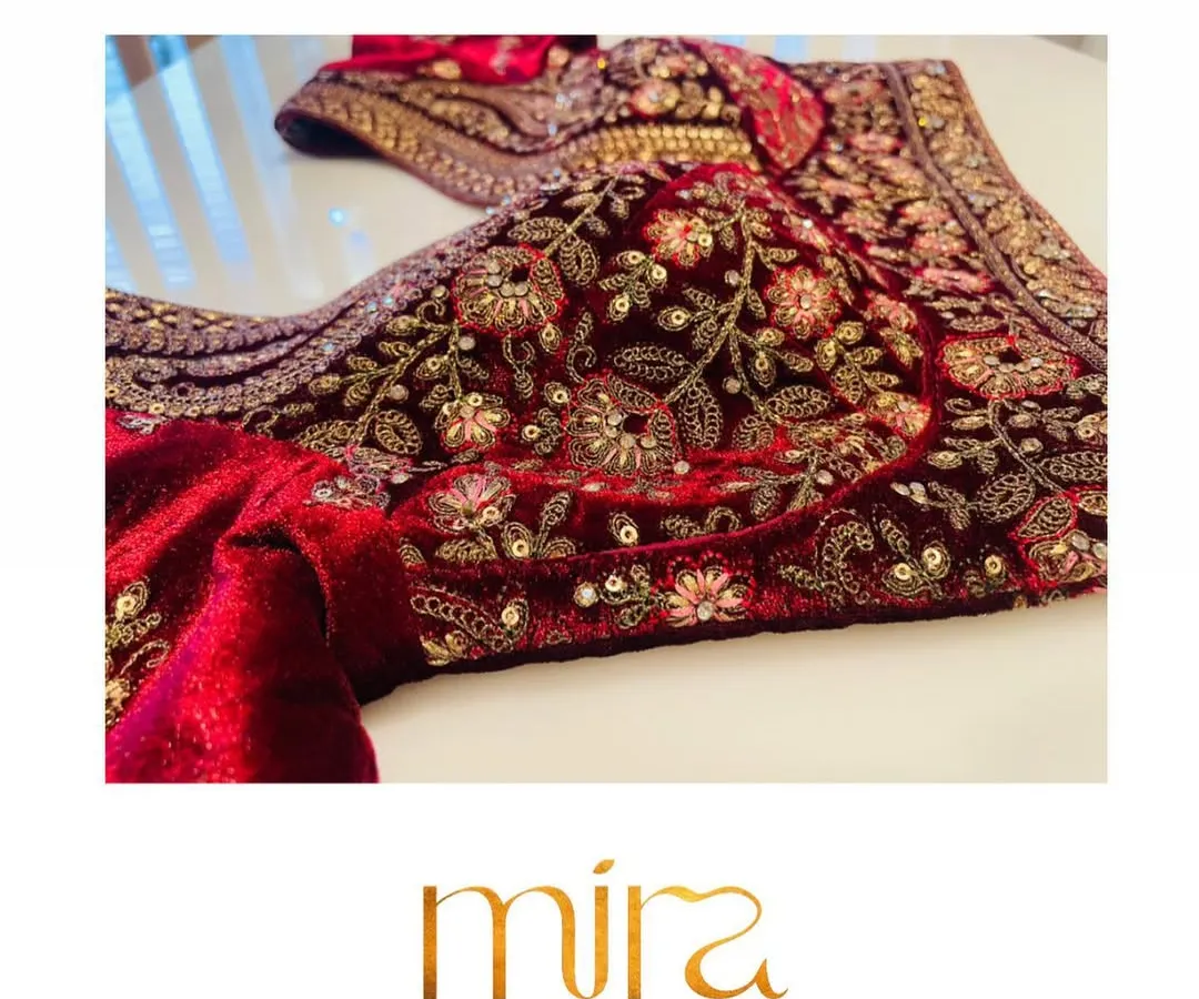 A close look at the rich Zardosi and thread work on a classic red velvet bridal blouse. This traditional design is a favorite for the main wedding ceremony, embodying timeless elegance and heritage craftsmanship.