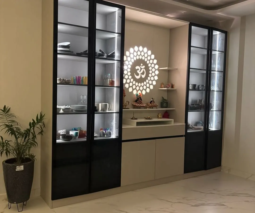 This custom unit seamlessly integrates a modern crockery display with a serene pooja mandir. It features black-framed glass shutters, internal LED lighting for the display sections, and a dedicated, beautifully lit space for worship, solving a common need in Indian homes.