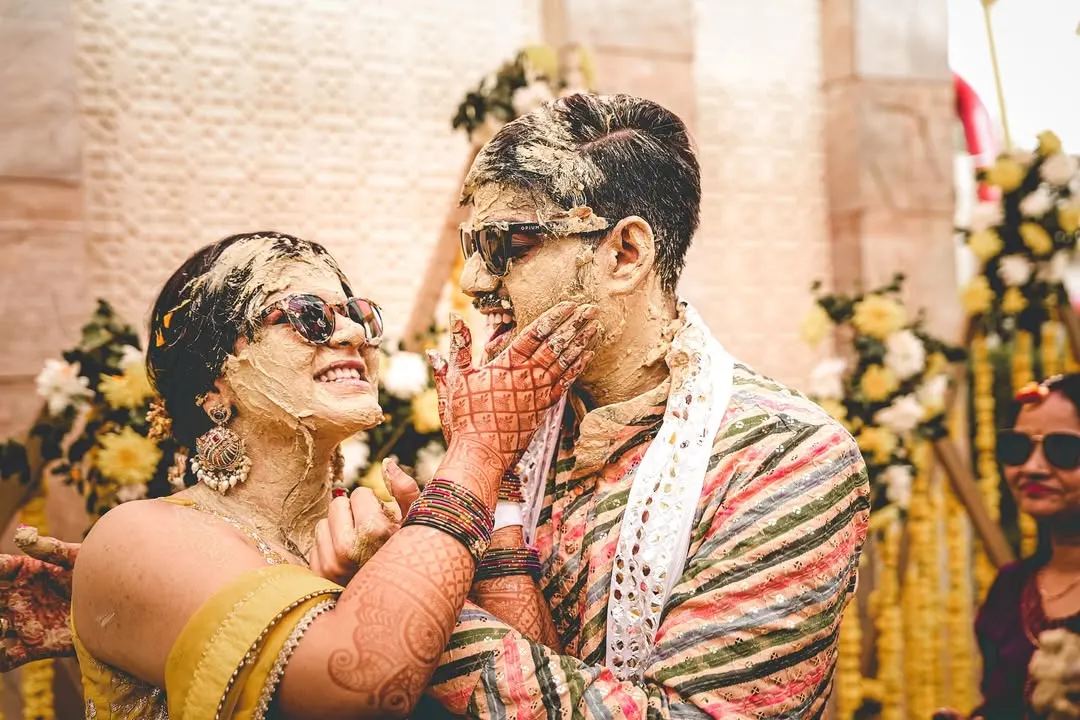 The Haldi ceremony is all about unrestrained joy, and we live for capturing it. This moment of the couple playfully smearing turmeric on each other, with genuine laughter and cool sunglasses, perfectly shows the fun and candid spirit we aim to freeze in time.
