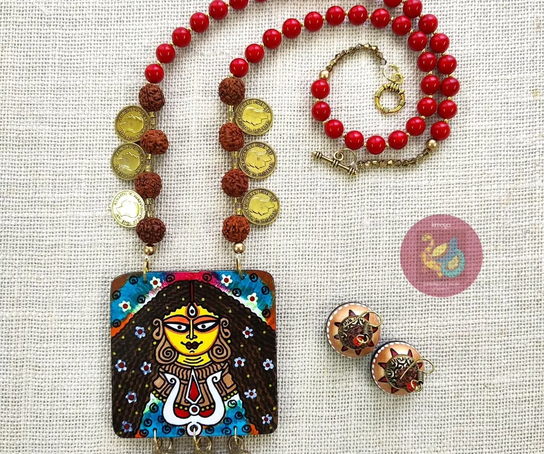 Feel the power of the goddess with this Durga necklace set. I painted this piece to be bold and protective, using a strong red and yellow palette. The set includes a detailed MDF pendant with brass ghungroos, wooden jhumkas, and sacred rudraksha beads.