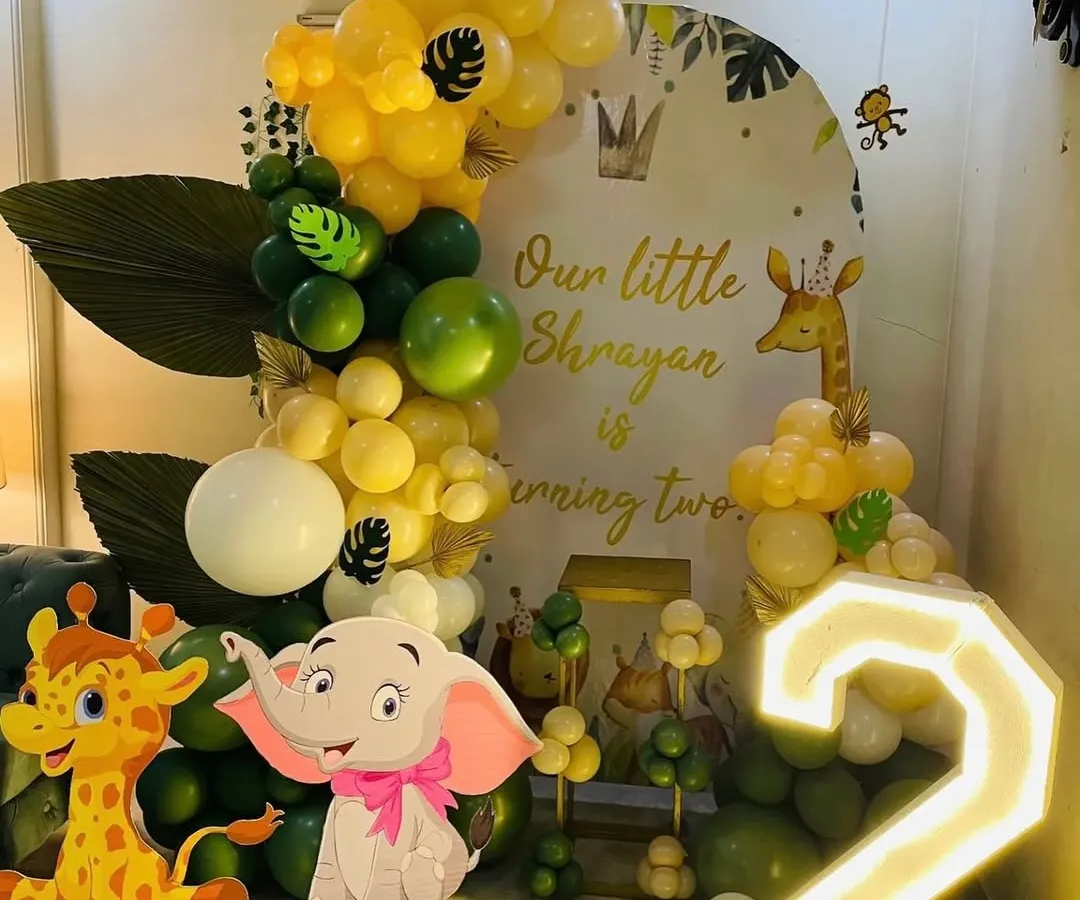 My jungle theme setups are a big hit with the kids. This one features cute elephant and giraffe cutouts, a personalized backdrop, and a big light-up number '2' for the birthday boy.