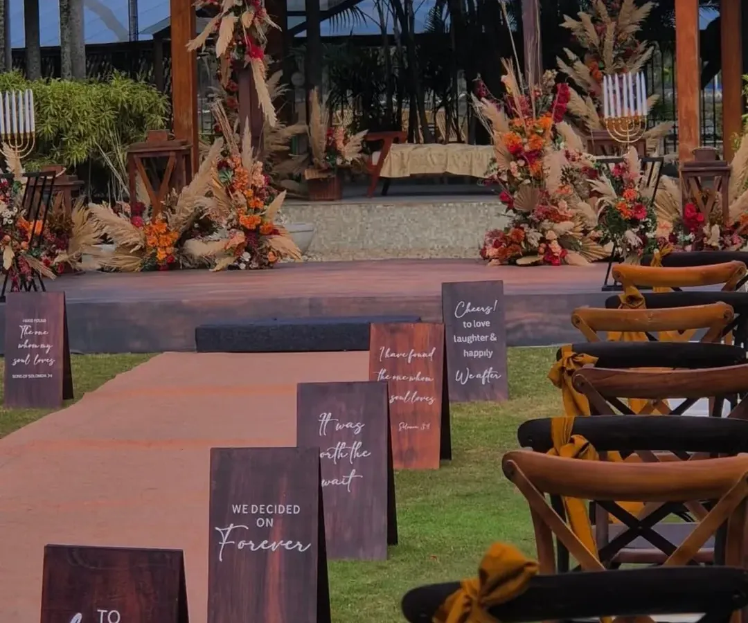 For this intimate outdoor wedding, I designed a boho-chic ceremony space using earthy florals and pampas grass. The personalized aisle signs, with quotes chosen by the couple, added a narrative touch that made the walk to the mandap deeply personal.