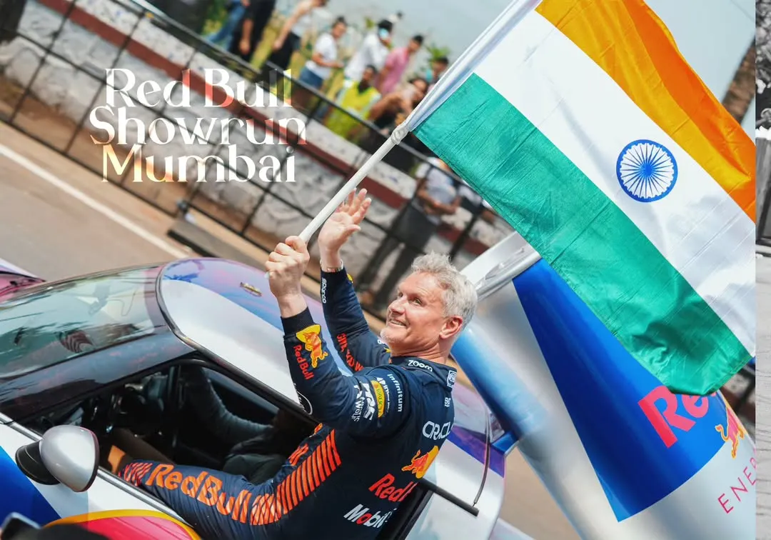 An iconic moment with F1 legend David Coulthard celebrating with the Indian flag at the Red Bull Showrun. This is the hero shot, the emotional peak of the event that tells a powerful story and creates a lasting memory.