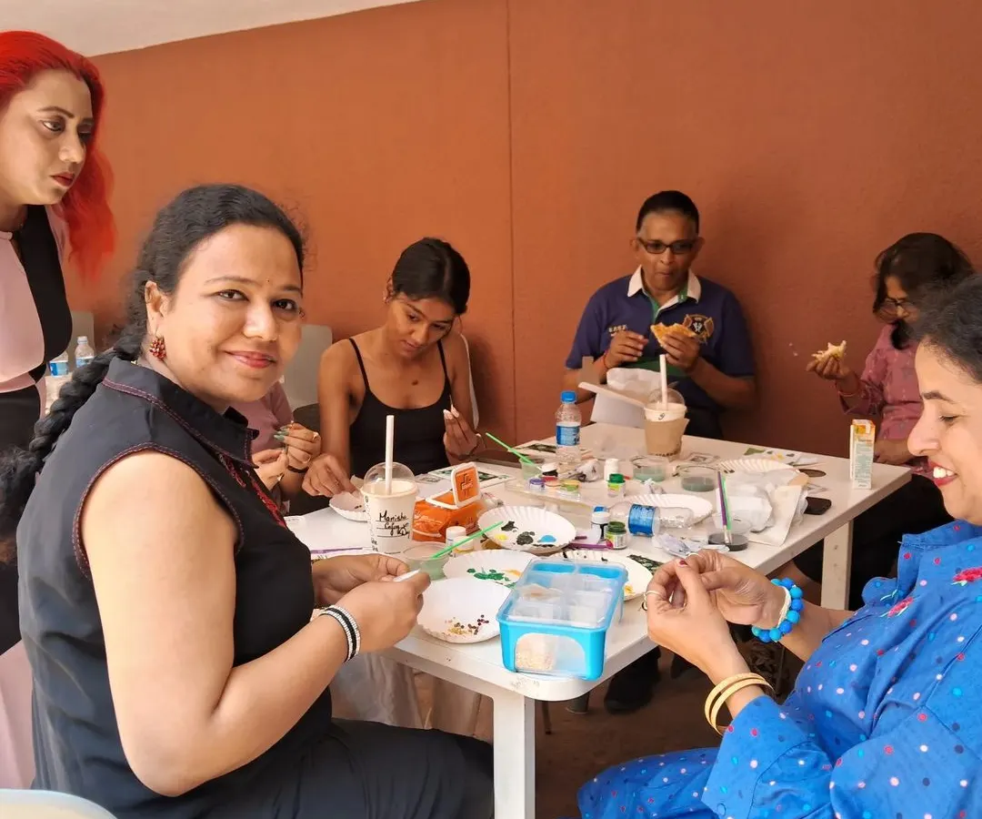 A candid moment from one of our interactive art classes. Participants are gathered around a table, sharing supplies and conversation as they work on their individual projects in a relaxed, communal setting.