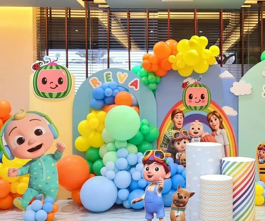 A vibrant and immersive Cocomelon themed birthday party setup. This decoration features multiple character cutouts, rainbow-colored balloon garlands, and personalized backdrops to create a fun and recognizable world for the little ones.