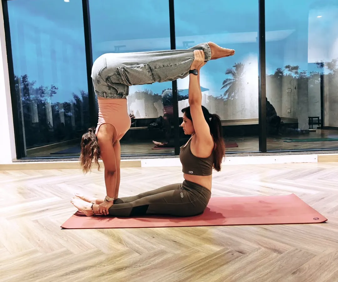 Acro Yoga is all about creating shapes and building trust. Here, my partner acts as a stable base while I practice an L-sit handstand, a pose that requires immense core strength and communication between us.