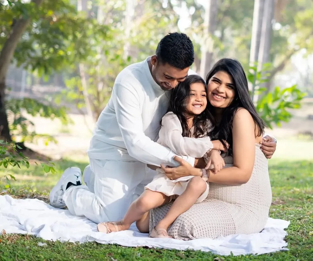 Love grows here. A beautiful family shares a warm hug in a sunlit park during their outdoor maternity session, celebrating the upcoming arrival of their new baby.