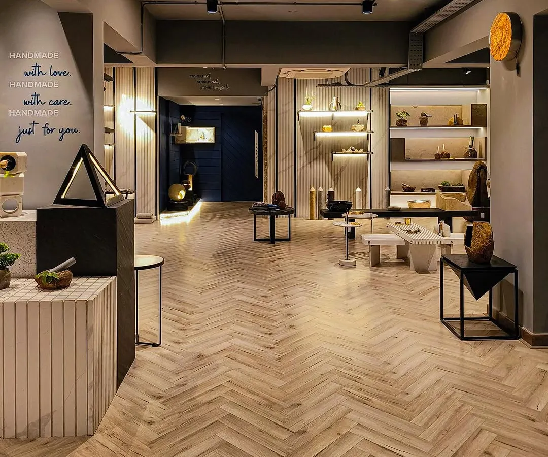 An expansive look at the Paarkhi stone boutique, where a herringbone wood floor harmonises with neutral-toned walls and thoughtfully placed product displays. The design uses open space and strategic lighting to create a serene, gallery-like experience for customers.