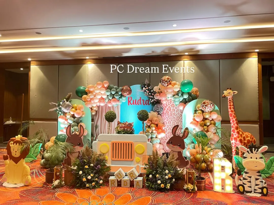 We brought the jungle to life for Rudra's first birthday with this large-scale safari theme decoration. The setup features a custom backdrop with a jeep cutout, friendly animal characters, and organic balloon garlands in a jungle-inspired color palette.