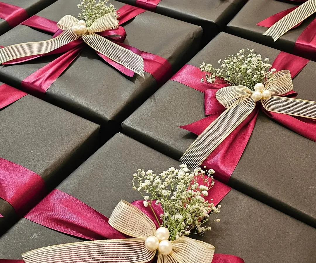 This is a great example of how I balance corporate identity with a touch of glamour. For a collaboration between Shoppers Stop and Axis Bank, I used a sophisticated dark grey wrap with bold magenta and cream satin ribbons, finished with delicate baby's breath and pearls. It's a chic and elegant look perfect for high-end corporate gifting.
