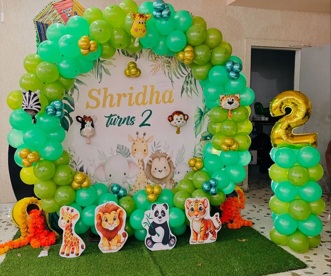 For a kid's second birthday, I created this fun jungle theme. The setup includes a custom backdrop with cartoon animals, a circular balloon arch in shades of green, and animal cutouts to bring the safari party to life.
