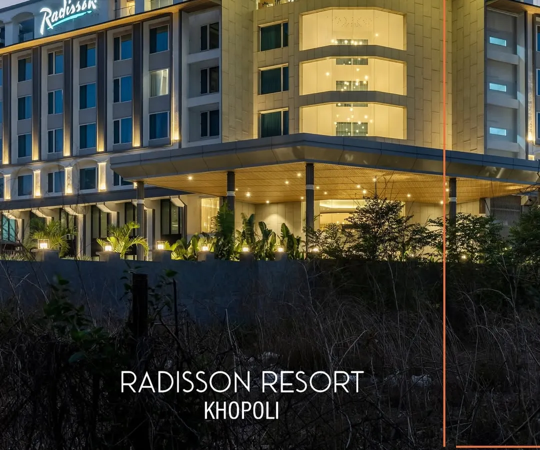 The contemporary facade of Radisson Resort, Khopoli, illuminated at dusk. The architecture balances clean lines with warm, inviting lighting, establishing its presence as a modern urban resort nestled in a natural landscape.