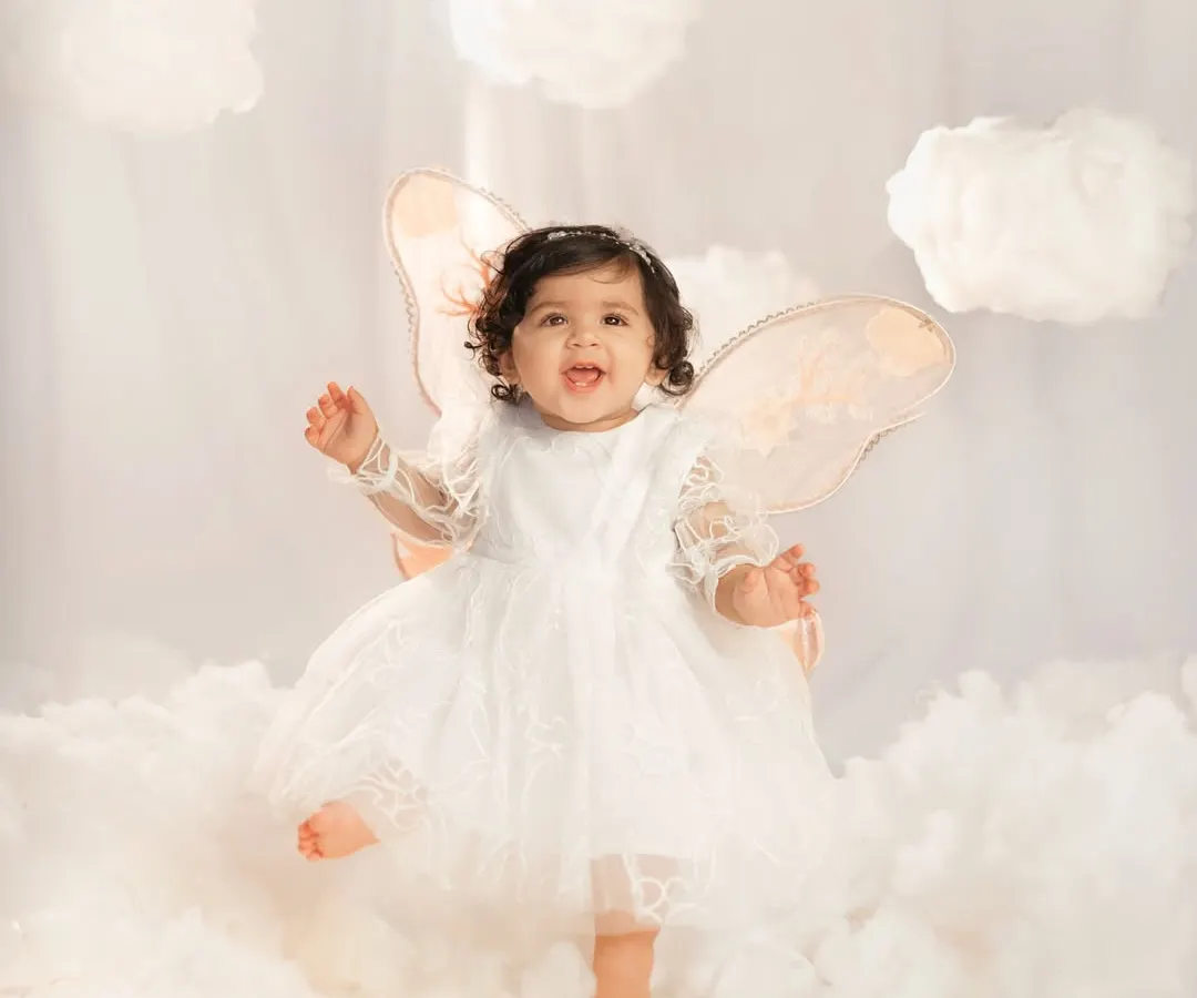 A little angel dancing on clouds for her first birthday. This is from my 'Journey to One Year' series, where I design magical studio setups like this dreamy cloud theme to celebrate your baby's biggest milestones.