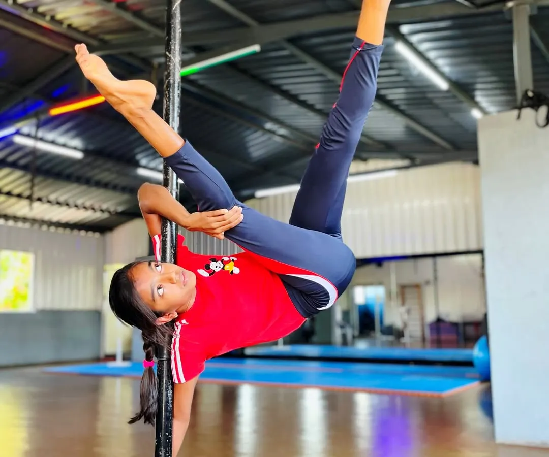 Defying gravity with grace and power. This incredible split on the pole is a testament to the strength, flexibility, and dedication our students develop. We guide each child to safely achieve amazing feats of pole fitness.