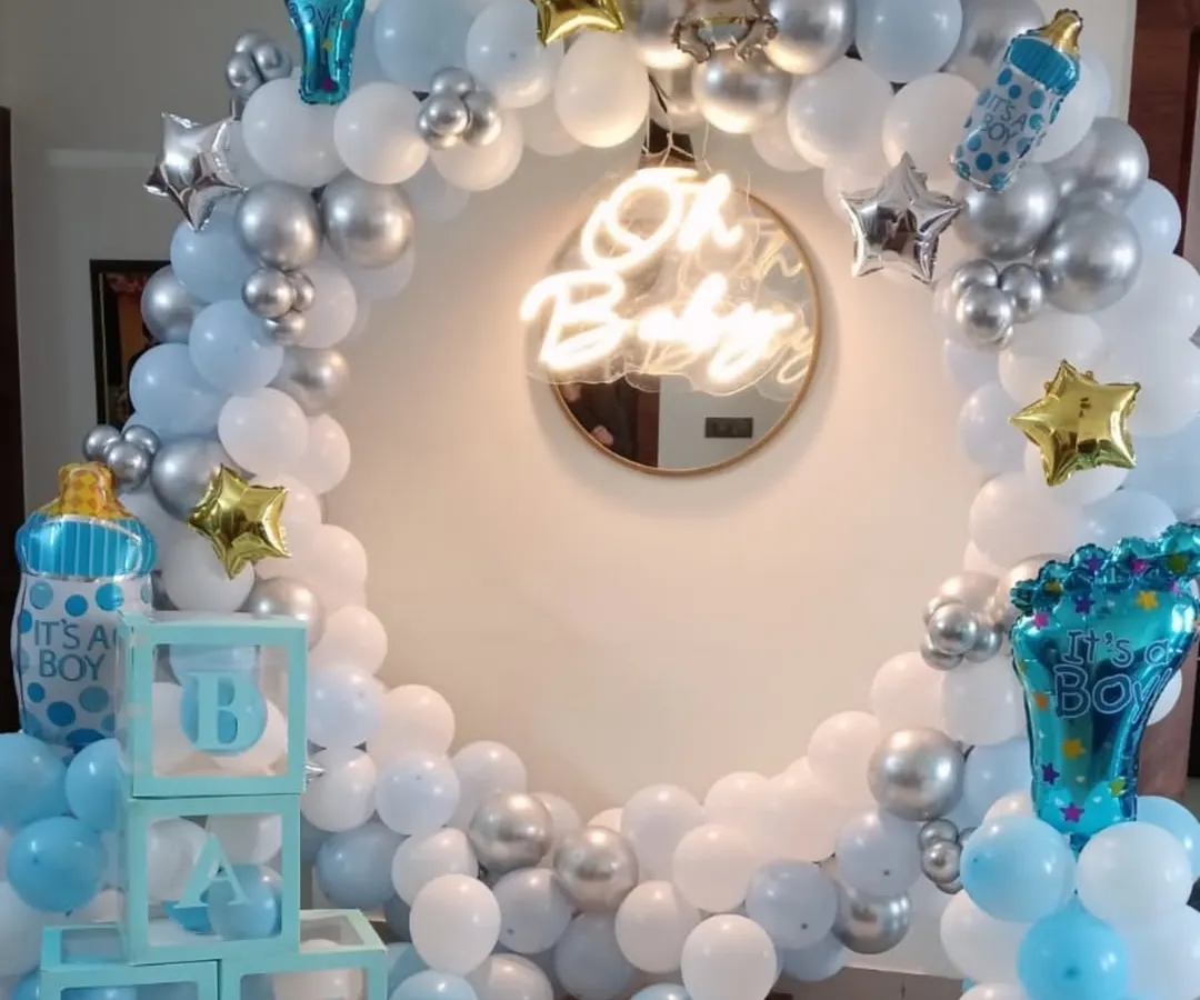 An elegant and modern 'Oh Baby' setup, perfect for a baby shower or welcome home party for a boy. This design is built around a full circular balloon arch in pastel blue, white, and chrome silver, with a central neon sign. I also include themed props like 'BABY' display boxes and foil balloons shaped like baby bottles.