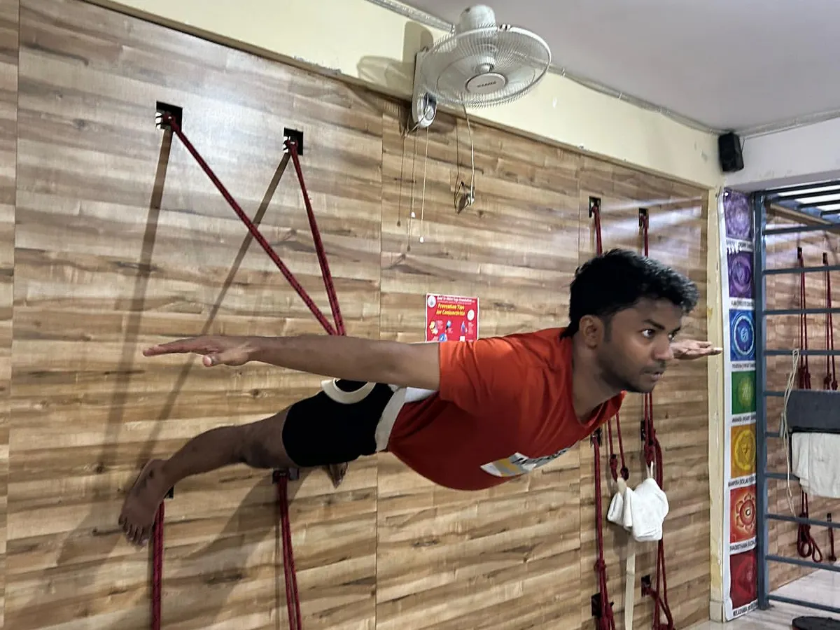 Using wall ropes is a technique I focus on to build exceptional core strength and body control. Here, a student holds a challenging horizontal pose, which decompresses the spine and strengthens the entire back and abdominal muscles. This is not a shortcut, but a tool for achieving correct form.