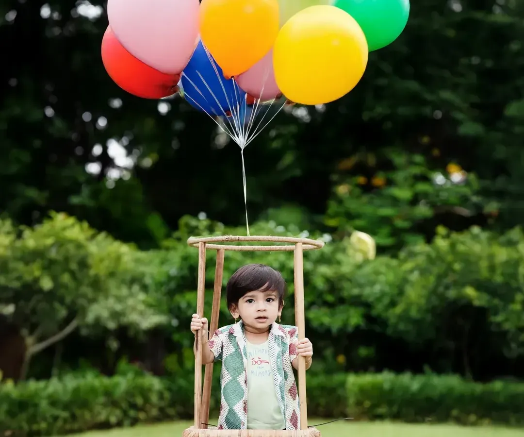 Up, up, and away! This hot-air balloon prop is a client favorite for first birthday shoots, creating a joyful and adventurous portrait against a beautiful outdoor backdrop in a Mumbai park.