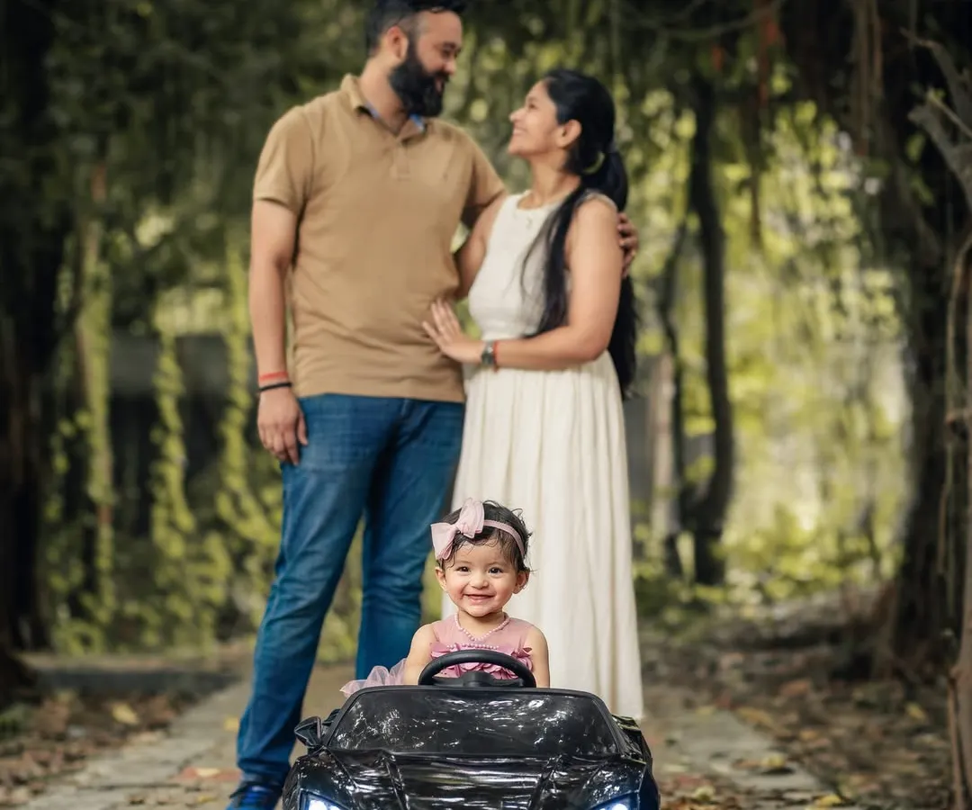 We love taking our sessions outdoors into Delhi's parks, where natural light and beautiful scenery create a relaxed atmosphere. This family portrait showcases a playful moment, with our miniature toy car adding a touch of fun for the little one.