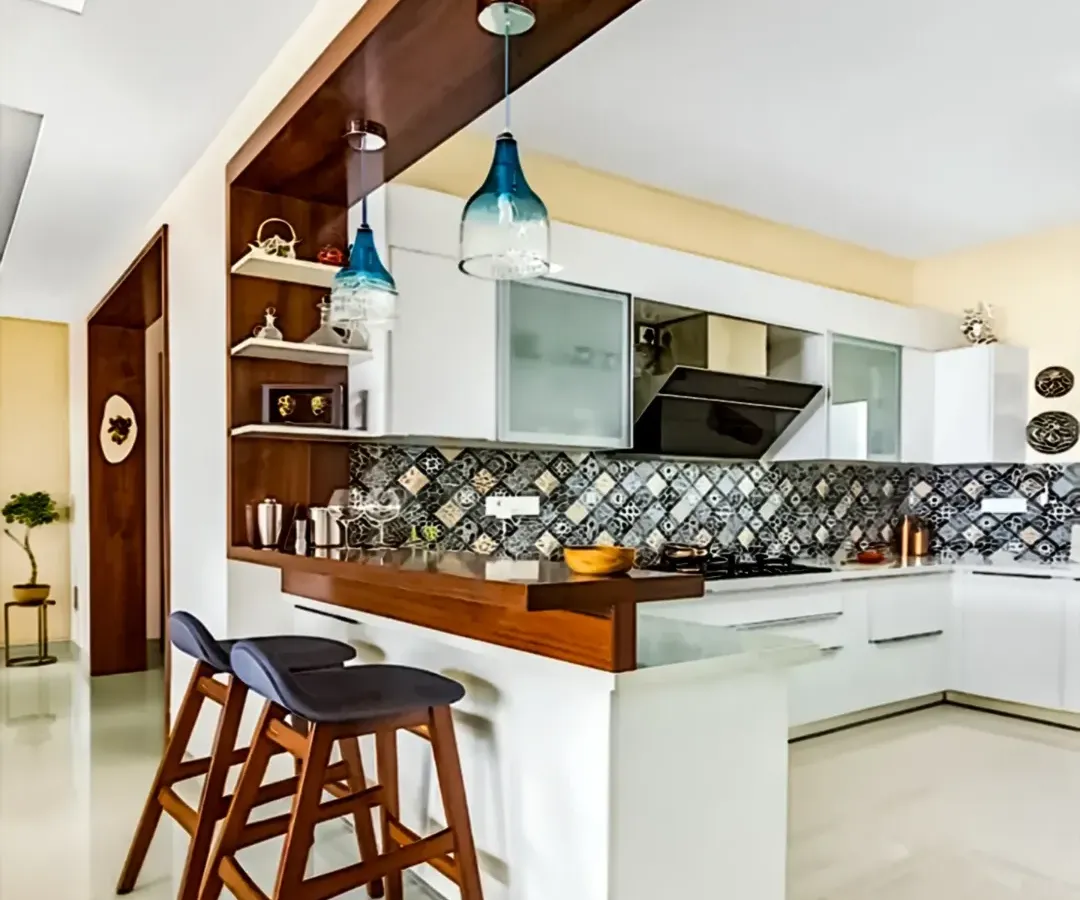 Our modular kitchens combine sleek aesthetics with smart functionality. This design features a stylish breakfast bar with pendant lighting, patterned backsplash tiles, and handleless white cabinets for a clean, contemporary look perfect for modern living.