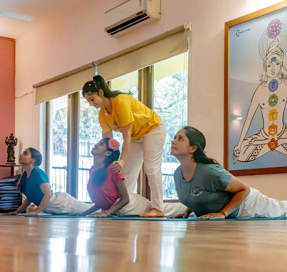 In our classes, you are never just a face in the crowd. We provide hands-on adjustments and personal guidance to ensure you are practicing safely and effectively, as seen here in this Bhujangasana (Cobra Pose) correction.