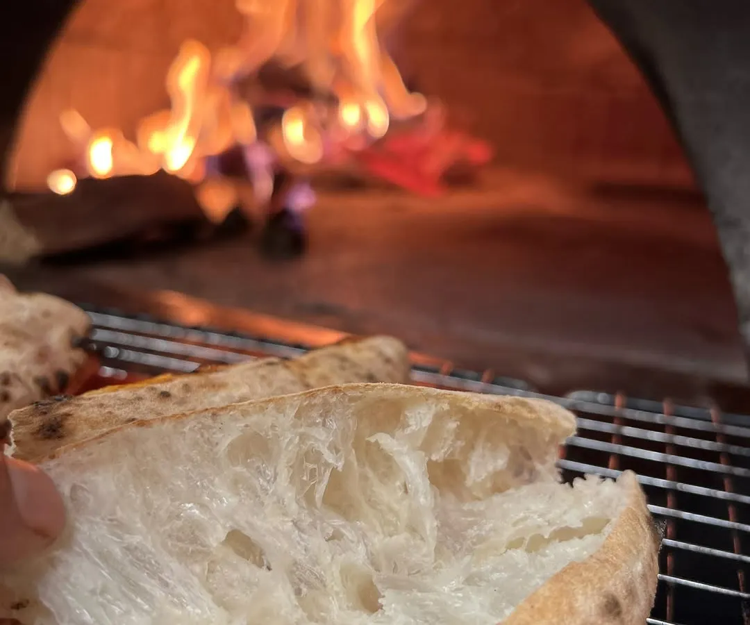 This is where the flavour is born. Our Neapolitan crust, with its soft, airy pockets, getting that perfect fire-kissed char from the wood oven. It's a difference you can taste.