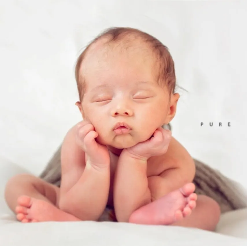 The classic 'froggy' pose is a favorite among parents. It requires patience and careful handling to safely position the baby, highlighting their delicate features and curled-up form against a simple, pure white backdrop.
