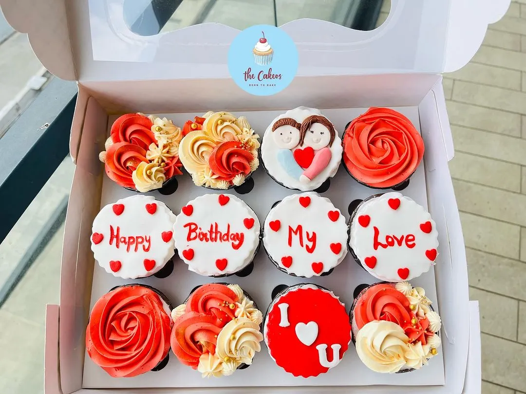 A box of my custom eggless cupcakes is the perfect way to send a personal message. This set was designed for a birthday, featuring hand-piped roses, a cute couple illustration, and the message "Happy Birthday My Love" spelled out across the treats.