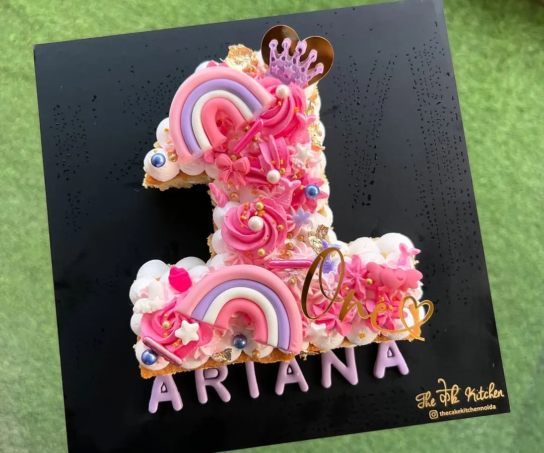 For Ariana's first birthday, I designed this pretty-in-pink number 1 monogram cake. It's decorated with buttercream swirls, custom acrylic rainbows, a little crown, and the birthday girl's name for a magical touch.