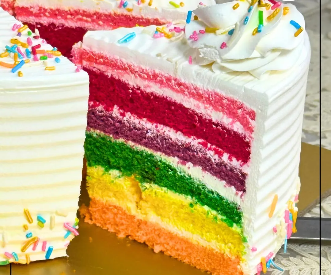 A slice of pure joy. Our Rainbow Cake features vibrant, soft layers of sponge with delicate cream cheese frosting in between, showing the fun and precision we put into our celebration cakes. It's a favorite for birthdays and happy occasions.