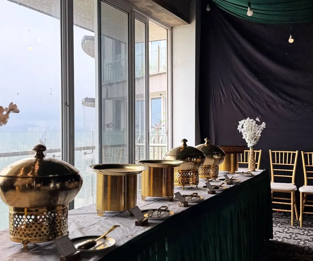 Our full-service catering includes creating a sophisticated ambiance. Here, you can see our elegant brass chafing dishes and coordinated green and gold decor, which we set up to ensure your event looks as incredible as the food tastes.