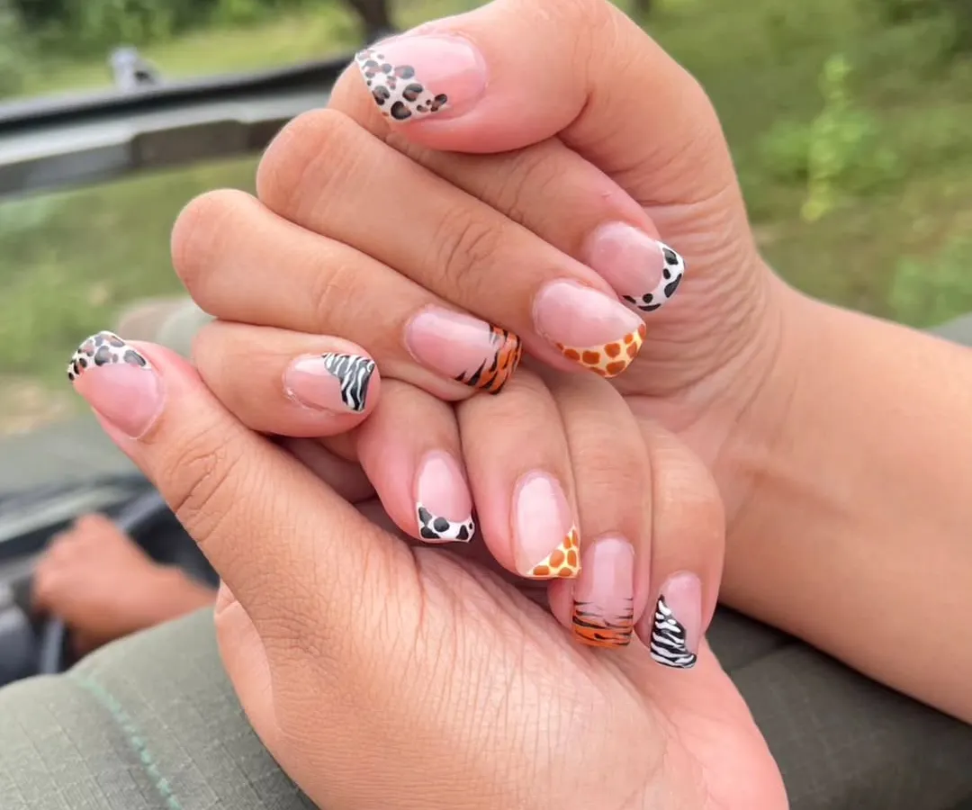 This set shows my skill with detailed, custom nail art, featuring different animal prints like leopard, giraffe, and zebra on each nail in a creative French tip style.