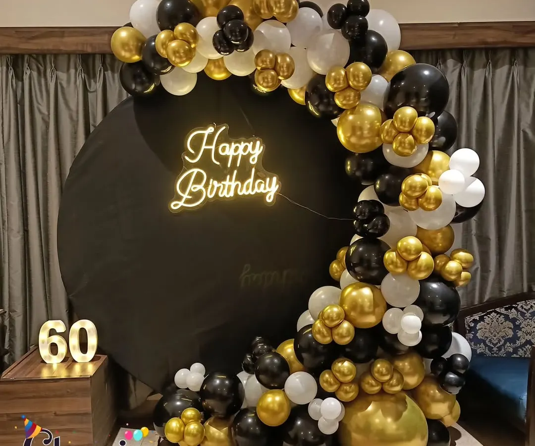 For milestone birthdays like a 60th, we design elegant setups. This one features a black and gold balloon semi-arch on a circular backdrop with a custom neon sign and marquee numbers.