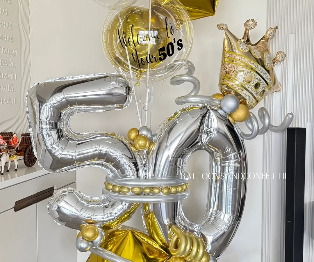 Celebrating a half-century in style! This grand 50th birthday balloon bouquet in silver and gold, complete with a crown, is designed to be a magnificent centerpiece for a milestone celebration.
