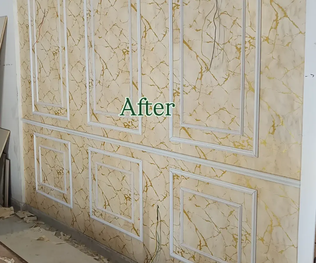 This is the finished look of a wainscoting project. I used white moulding to frame a luxurious gold-veined marble wallpaper, giving the entire wall an elegant and high-end appearance.
