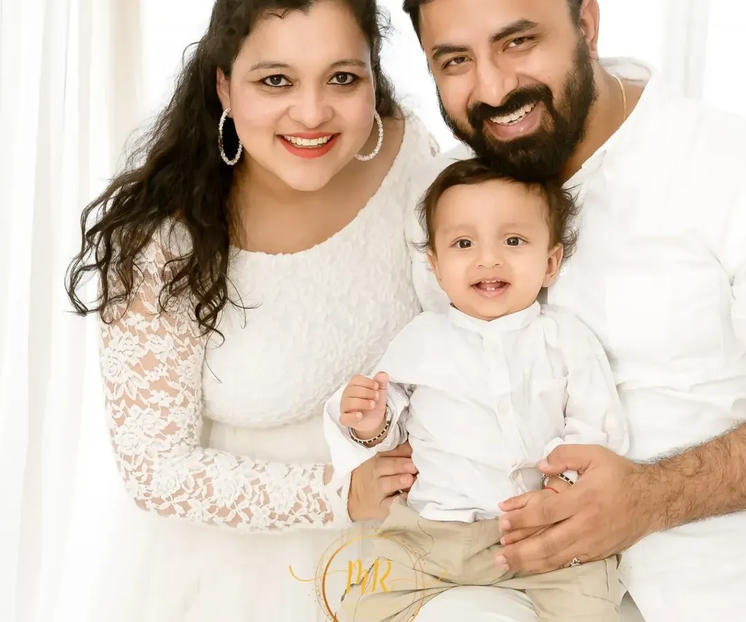 A bright and happy family portrait with both parents and their baby boy, all dressed in white. I always encourage parents to join in, as these moments of connection are truly priceless.