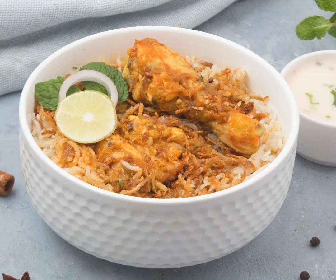 A classic bowl of our chicken dum biryani, made with fragrant long-grain rice and tender chicken pieces. We serve it with a side of cooling raita to balance the authentic spices.