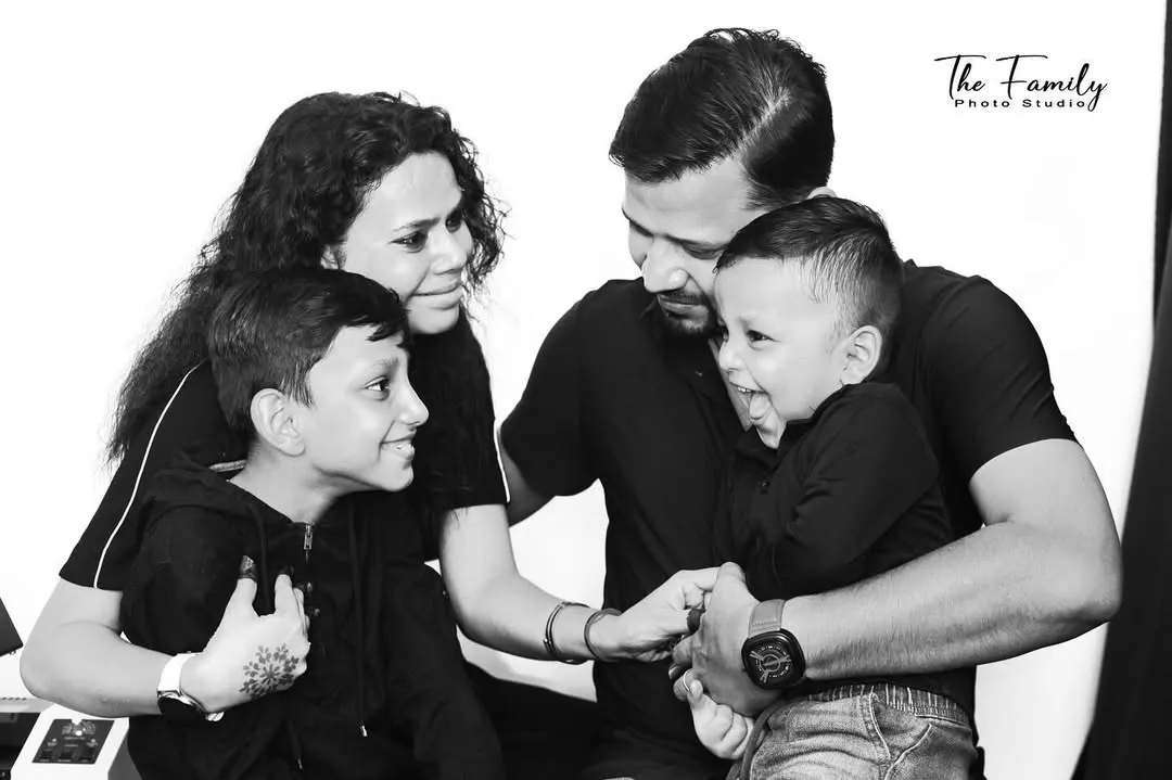 A candid family moment captured in the studio. Using a black and white format helps focus on the pure joy and interaction between parents and their children, creating a timeless memory.