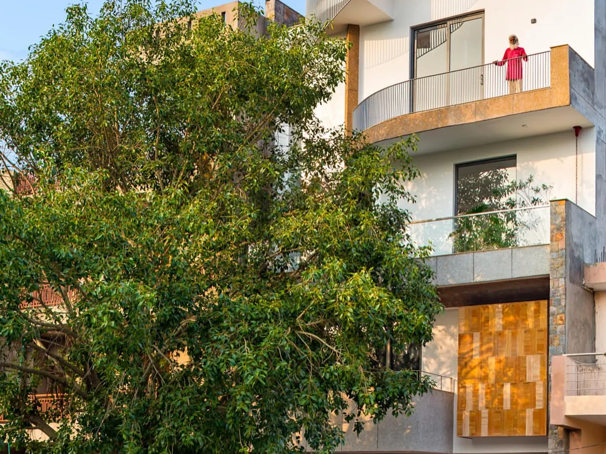 The exterior of the People Tree House, named 'Ashvattha', is designed in deference to the magnificent sacred fig tree that anchors the site. The architecture embraces the tree, making it the focal point and creating a sustainable residence where nature is not just outside, but a fundamental part of the home itself.